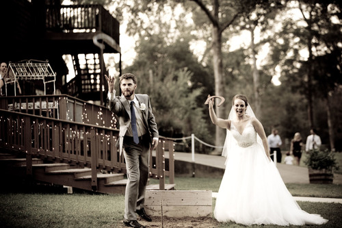 A bride and groom having a friendly game of horseshoes just off the deck.